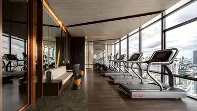 a gym with a row of treadmills in a building at The Bangkok Thonglor in Bangkok