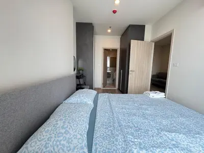 a bedroom with a bed with a blue comforter at NUE District Rama 9 Condo in Bangkok
