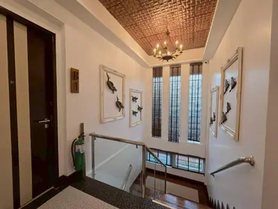 a hallway with a staircase with a chandelier at Casa Le Damuz in Bangkok