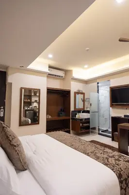 a bedroom with a large white bed and a television at Casa Le Damuz in Bangkok