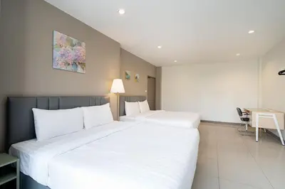 two beds in a hotel room with a desk and a table at Grand 3BR Townhouse in the Heart of BKK - Emsphere in Khlong Toei