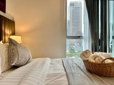 a bedroom with a basket of towels on a bed with a window at Cozy City BTS Nana | Pool, Sauna & Gym 38th Floor in Makkasan