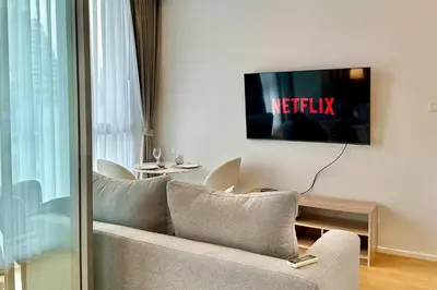 a living room with a couch and a tv on a wall at Cozy City BTS Nana | Pool, Sauna & Gym 38th Floor in Makkasan