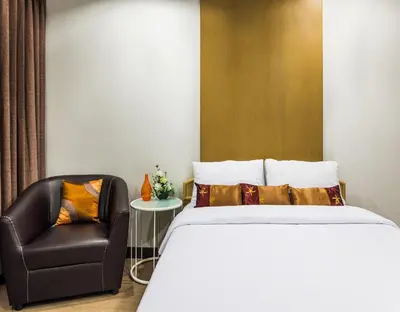 a bedroom with a bed and a chair at BB Garden Resort in Bangkok
