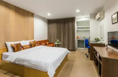 a bedroom with a bed and a desk and a television at BB Garden Resort in Bangkok