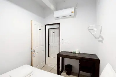 a bedroom with a desk and a white wall at xx Mitr inn Khaosan ถนนตะนาว in Bangkok
