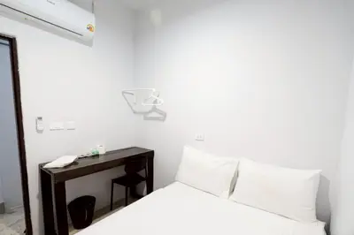 a bedroom with a bed and a desk with a phone at xx Mitr inn Khaosan ถนนตะนาว in Bangkok