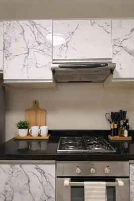 a kitchen with a stove and white marble walls at 166 Living in Bangkok