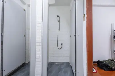a walk in shower in a bathroom with white walls at High Friend Hostel in Phra Khanong