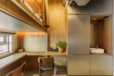 a kitchen with a sink and a counter with a chair at The District Hostel Ekkamai in Sathani Khlong Tan
