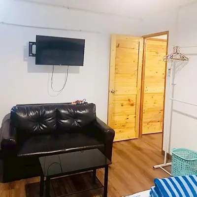 a living room with a leather couch and a television at Boontharika Place Cozy Room Popular Condo near IMPACT Muangthong in Thung Si Kan