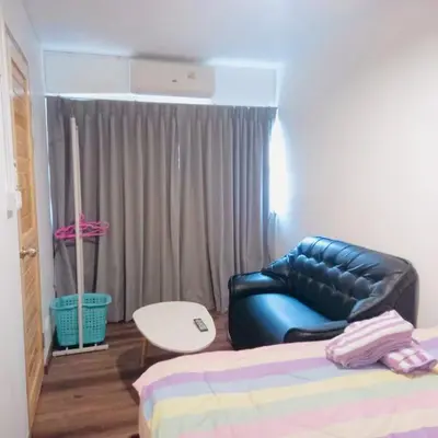 a bedroom with a black leather chair and a table at Boontharika Place Cozy Room Popular Condo near IMPACT Muangthong in Thung Si Kan