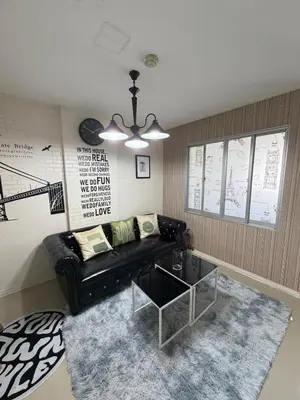 a living room with a black leather couch and a table at Stadium Area Stay Famous Thai Street Food in Bangkok