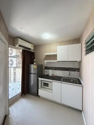 a kitchen with white cabinets and a black refrigerator at Stadium Area Stay Famous Thai Street Food in Bangkok