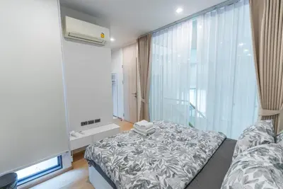 a bedroom with a bed and a large window at Heaven Sukhumvit 62Villa in Bangkok