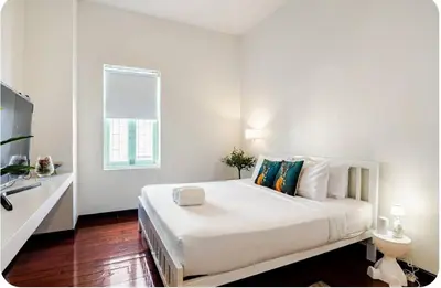 a white bedroom with a large white bed with a window at Baan Surawong 390 Heritag house in Chinatown