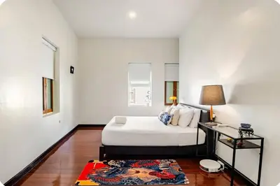 a white bedroom with a bed and a rug at Baan Surawong 390 Heritag house in Chinatown