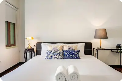 a bedroom with a white bed with two towels on it at Baan Surawong 390 Heritag house in Chinatown