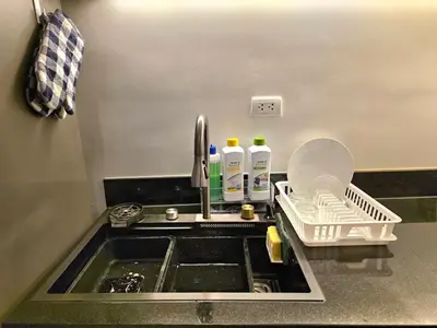 a kitchen sink with a dish drying rack next to it at Baan Surawong 390 Heritag house in Chinatown