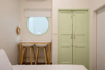 a bedroom with a bed and a window and a table at Baan Surawong 390 Heritag house in Chinatown