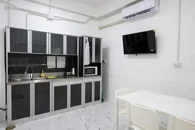 a kitchen with black cabinets and a sink and a tv at ดอนเมือง 307 Near DMK Airport BTS Wat PhraSi in Bang Khen