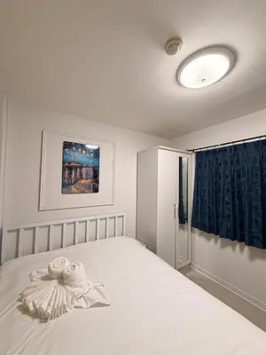 a bedroom with a white bed with a blue curtain at Best Value Condo Lumpini Rajamangala in Sathani Khlong Tan