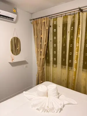a bedroom with a bed with white sheets and a curtain at Best Value Condo Lumpini Rajamangala in Sathani Khlong Tan