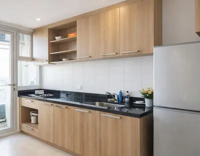 a kitchen with wooden cabinets and a white refrigerator at Hive Sathorn SkyCorner Suite, BTS and 7-11 front in Bangkok