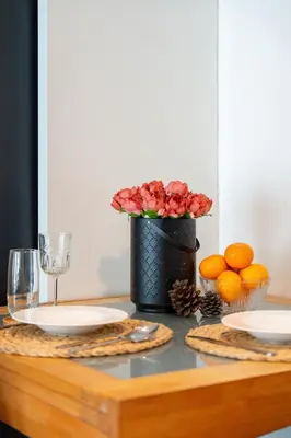 a table with plates and a vase of flowers and oranges at Lucky 808 2BedRoom 100sqm BTS Chidlom in Bangkok
