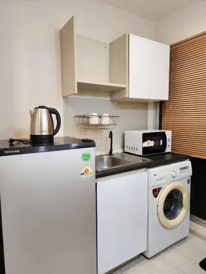 a kitchen with a washing machine and a microwave at Homely Condo Minimal Style Near BTS Silom line in Bang Khun Thian