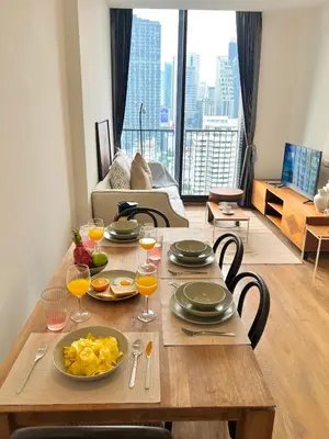 a wooden table with plates of food and glasses of orange juice at WalkToBTS>EMDistrict/CityViewPool&Gym/WiFi/Washer in Khlong Toei
