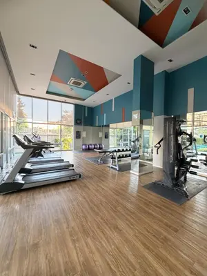 a gym with treadmills and ellipticals in a room at Lumpiniville Sukhumvit in Bangna