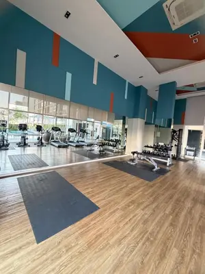 a gym with a large room with wooden floors and blue walls at Lumpiniville Sukhumvit in Bangna