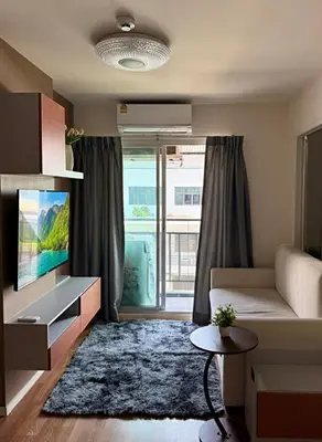 a living room with a couch and a large window at Lumpiniville Sukhumvit in Bangna