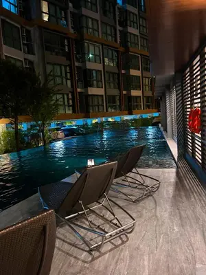 a group of chairs sitting next to a pool in a building at Luxury apartment near On Nut BTS station with swimming pool in Amphoe Phra Khanong