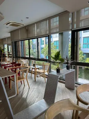a restaurant with tables and chairs and windows at Luxury apartment near On Nut BTS station with swimming pool in Amphoe Phra Khanong