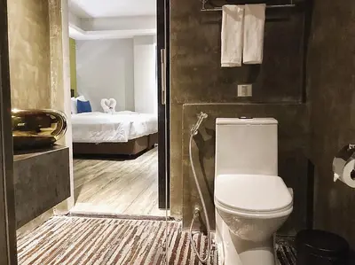 a bathroom with a toilet and a bedroom at Aspira D'Andora Sukhumvit 16 - Asoke in Bangkok