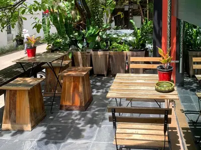 a group of wooden tables and benches with plants at Aspira D'Andora Sukhumvit 16 - Asoke in Bangkok