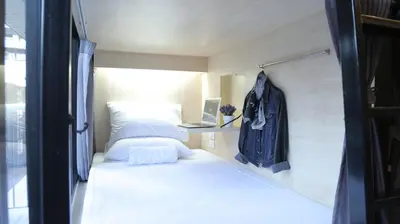 a small room with a bed and a laptop on a shelf at Lamurr Sukhumvit 41 in Bangkok