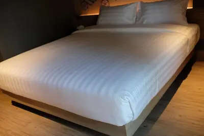 a large bed with white sheets and pillows at NAP Hotel Bangkok in Bangkok