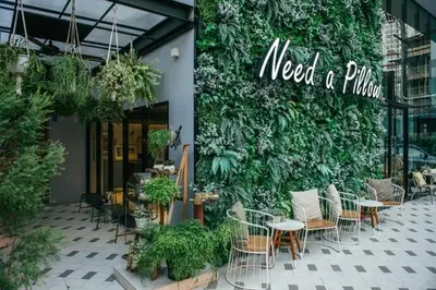 a restaurant with tables and chairs and a green wall at NAP Hotel Bangkok in Bangkok