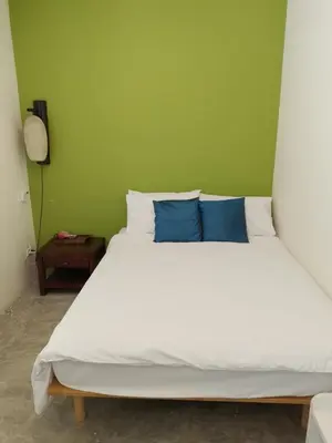 a bedroom with a white bed with blue pillows at Udee Bangkok Hostel in Bangkok