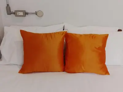 two orange pillows sitting on top of a bed at Udee Bangkok Hostel in Bangkok