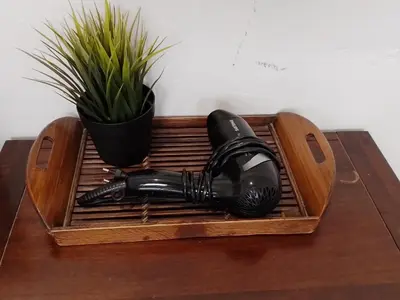 a hair dryer on a wooden tray on a table with a plant at Udee Bangkok Hostel in Bangkok