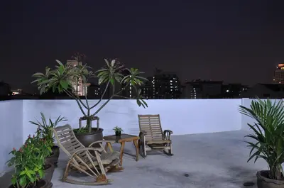 two chairs and a table on a rooftop at night at Udee Bangkok Hostel in Bangkok