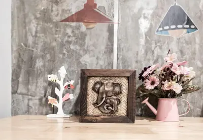 a picture of an elephant in a picture frame on a table with flowers at Check-in My Hostel in Bangkok