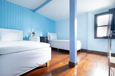 a blue room with two beds and a tub at Check-in My Hostel in Bangkok
