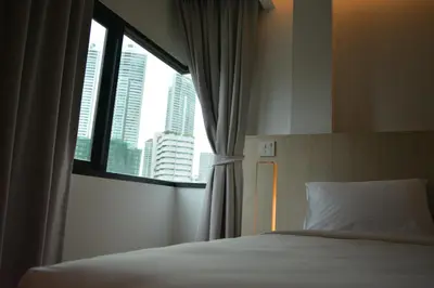 a bedroom with a bed and a window with skyscrapers at Rezt Bangkok in Bangkok