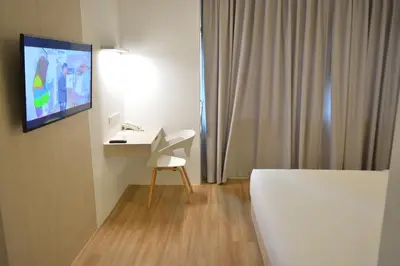 a room with a bed and a chair and a tv at Rezt Bangkok in Bangkok