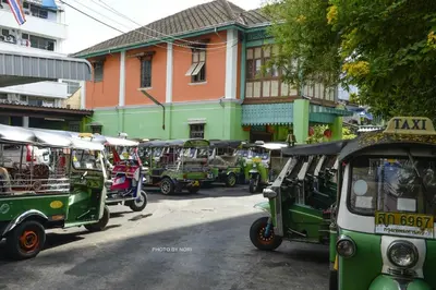 a group of green vehicles parked in front of a building at The Backpack Hostel in Bangkok